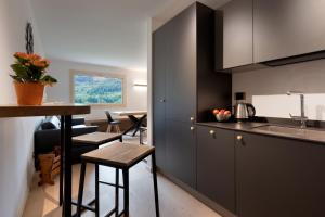 una cocina con armarios negros, una mesa y una encimera en Casa Paolina - Alpine Stay Apartments, en Tesero
