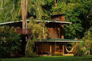 a house with a balcony and a tree at Casa Heliconia - spacious, big garden, close to the beach in Puerto Viejo