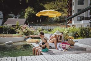 a family sitting on a dock by a pool at Superior Sport und Familienresort Alpenblick in Zell am See