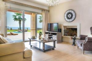 a living room with a couch and a tv and a fireplace at Astounding Seafront Kefalonia Villa - 3 Bedrooms - Villa Alegria - Private Pool and Amazing Sea Views - Minies in Kefallonia