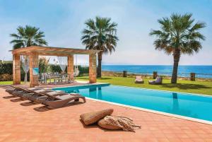 a swimming pool with chairs and a gazebo at Astounding Seafront Kefalonia Villa - 3 Bedrooms - Villa Alegria - Private Pool and Amazing Sea Views - Minies in Kefallonia