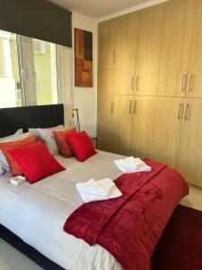 Un dormitorio con una cama grande con almohadas rojas. en Oceania bay village Pyla, en Lárnaca 16 fotos más