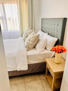 1 cama con sábanas blancas y almohadas en una habitación en Makarios en Pretoria