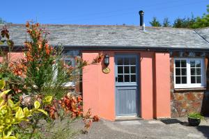 a small red cottage with a blue door at The Linhay in Hartland