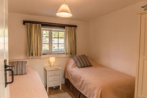 1 dormitorio con 2 camas y ventana en The Linhay en Hartland