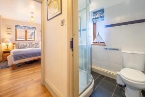 uma casa de banho com um chuveiro, um WC e uma cama em Monkey Puzzle Cottage em Snettisham