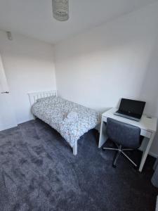 a bedroom with a bed and a desk with a laptop at Sunset Cottage in Stockton-on-Tees