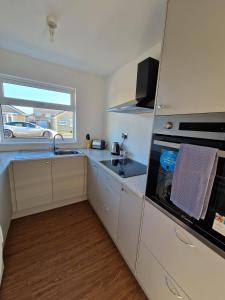 a kitchen with white cabinets and a sink and a window at Sunset Cottage in Stockton-on-Tees