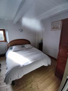 Schlafzimmer mit einem weißen Bett mit einem Kopfteil aus Holz in der Unterkunft Les Gites de TY Dreux Monts d'arrée in Saint-Thégonnec