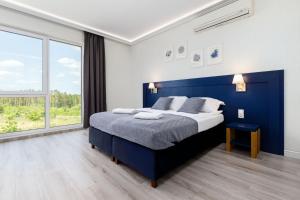 a bedroom with a blue bed and a large window at Nowoczesne apartamenty Jezioro Ukiel Zatoka Miła Plaża Miejska in Olsztyn