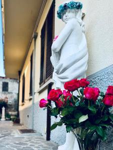 Una statua di una ragazza con delle rose in un vaso. di B&B Corte sul Naviglio a Cernusco sul Naviglio