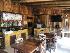 een eetkamer met houten muren en tafels en een tv bij RECANTO VERDES VALES in Palhoça