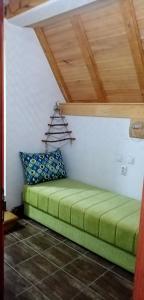 a green bed in a room with a wooden ceiling at StaroplaninSki Apartments in Crni Vrh +77 photos