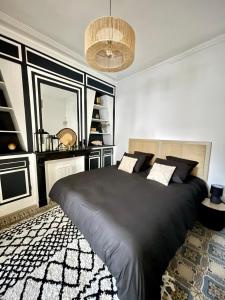 - une chambre avec un grand lit noir et un lustre dans l'établissement L'Art appart' - T2 - Lit King Size - Proche centre, à Amiens