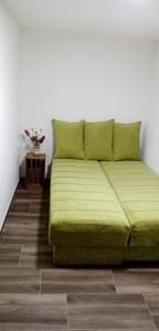 a green bed in a white room with a table at StaroplaninSki Apartments in Crni Vrh