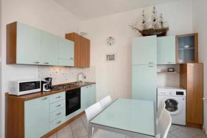 a kitchen with white cabinets and a table and a microwave at Frida apartments in Sanremo