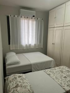um pequeno quarto com 2 camas e uma janela em Pousada cravo & canela em Maringá