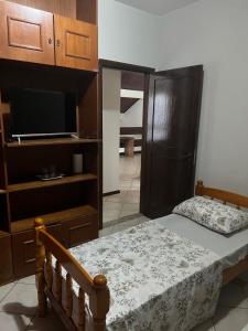 a bedroom with a bed and a tv and a cabinet at Pousada cravo & canela in Maringá
