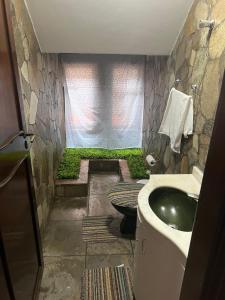 baño con lavabo y pared de piedra en Pousada cravo & canela en Maringá