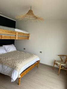 a bedroom with a bunk bed and a chair at Cuatro Islas Lodge del Mar Cabaña Isla Damas in Choros