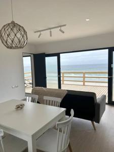 a living room with a table and chairs with a view of the ocean at Cuatro Islas Lodge del Mar Cabaña Isla Damas in Choros