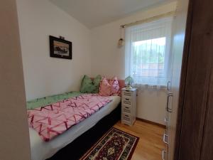 a bedroom with a bed with pink sheets and a window at Bungalow Lindenweg in Bad Ischl