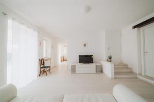 a white living room with a tv and a couch at Civiconr3 in Sona