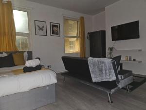 een slaapkamer met een bed, een stoel en een televisie bij LiveStay-Studio Flat in Dalston in Londen