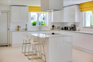 a kitchen with white cabinets and a sink and stools at Pine Cliffs Village in Albufeira