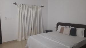 a bedroom with a white bed and a window at INAS Guest House in Canacona