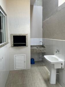 Baño de azulejos blancos con lavabo y aseo en Apartamento Fátima PARA FAMÍLIA, en Balneário Camboriú