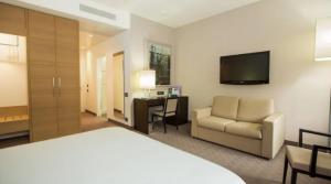 um quarto de hotel com uma cama, uma cadeira e uma secretária em Ariha Hotel Cosenza em Cosenza