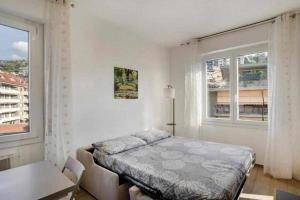 a white bedroom with a bed and two windows at Ninfea apartments in Sanremo