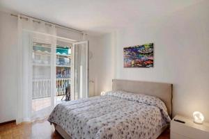 a white bedroom with a bed and a window at Ninfea apartments in Sanremo