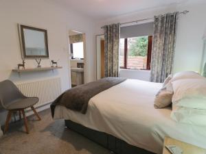 ein Schlafzimmer mit einem Bett, einem Stuhl und einem Fenster in der Unterkunft Hollys Hideaway in Castle Douglas