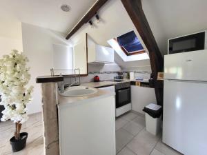 eine weiße Küche mit einer Spüle und einem Kühlschrank in der Unterkunft Le Nouvo : bel appartement entièrement rénové in Corbeil-Essonnes