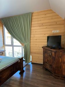 um quarto com uma cama e uma televisão de ecrã plano em Olko House em Yaremche