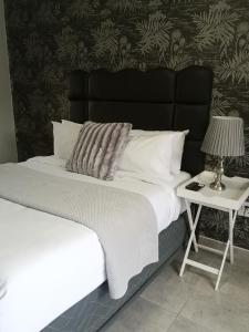 a bed with a black headboard and a table with a lamp at Boontjieskraal in Kimberley