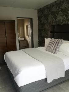 ein großes weißes Bett in einem Schlafzimmer mit einem Spiegel in der Unterkunft Boontjieskraal in Kimberley