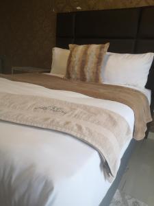 a large white bed with a blanket and pillows at Boontjieskraal in Kimberley
