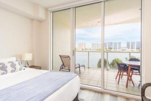 a bedroom with a bed and a balcony with a table and chairs at Marina Bay 46 in Miami Beach