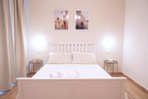 a white bed in a room with two pictures on the wall at La Bifora in Tivoli