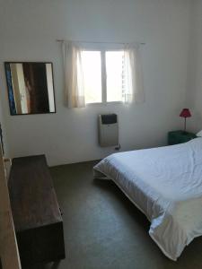 a bedroom with a white bed and a window at Los Leones in La Cumbre