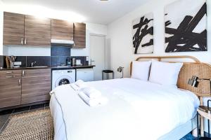 een slaapkamer met een wit bed en een keuken bij Studio équipé à 5 minutes de Paris - Montreuil -II in Montreuil