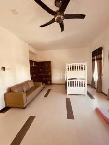 a living room with a ceiling fan and a crib at Maxwell Merpati Taiping Homestay in Kamunting