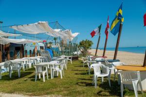 un montón de mesas y sillas en la playa en Residence Baiadosol, en Lido di Fermo