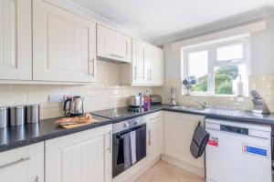 a kitchen with white cabinets and black counter tops at Trendy Sea View 2 bedroom Sleeps 6 - Free Parking in Bournemouth