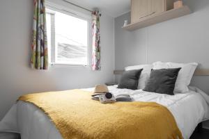 a bedroom with a bed with a yellow blanket and a window at Bontempo Village in Piriac-sur-Mer