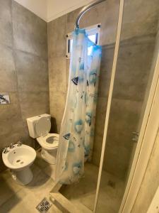 ein Badezimmer mit Toilette und Duschvorhang in der Unterkunft Hotel El Faro in Villa Gesell