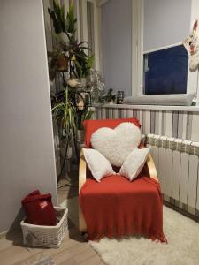 einen roten Stuhl mit Kissen und einer roten Decke in der Unterkunft Comfort StudioCity with balcony in Kamjanez-Podilskyj